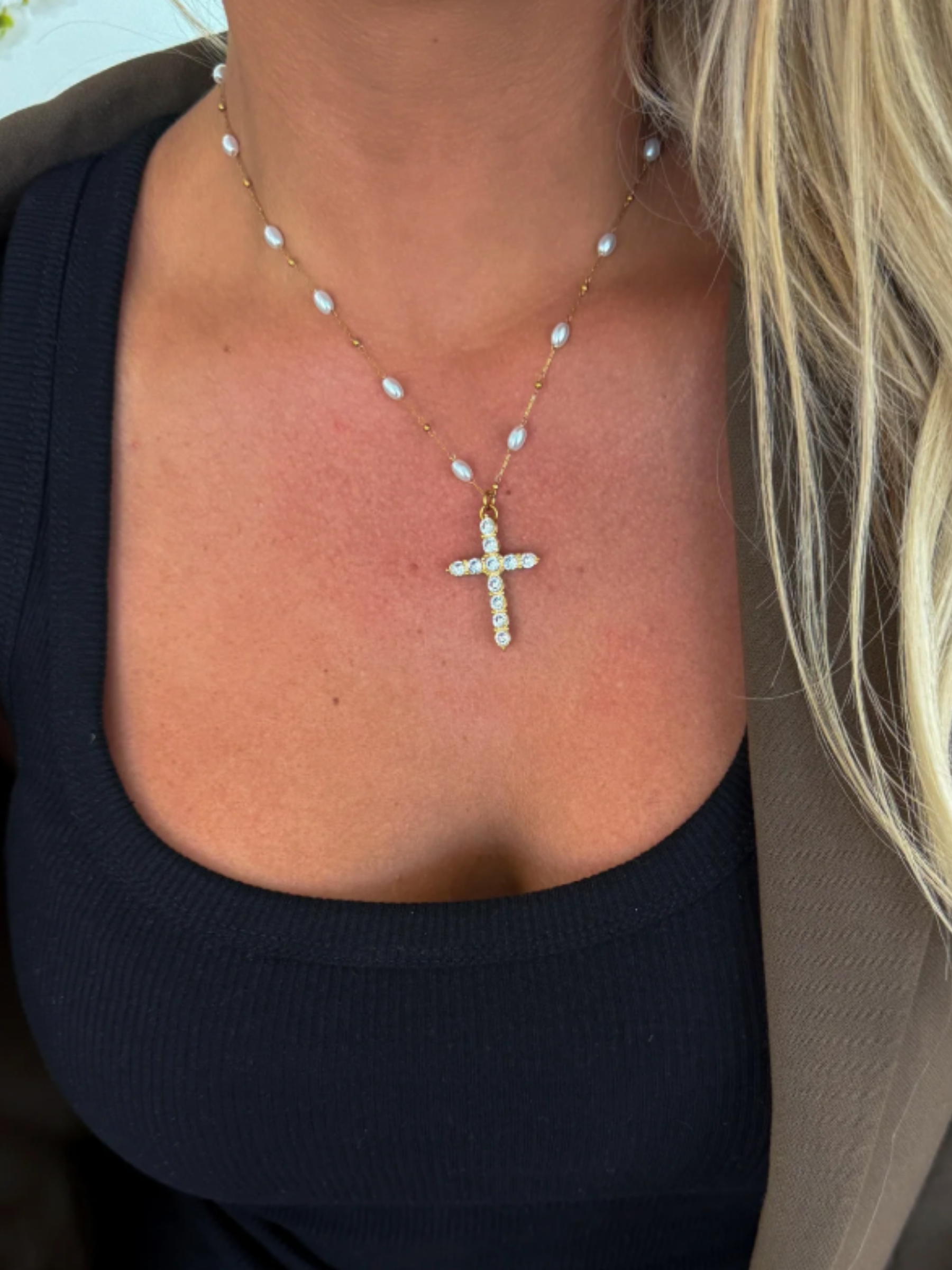 Necklace with a cross pendant worn by a person